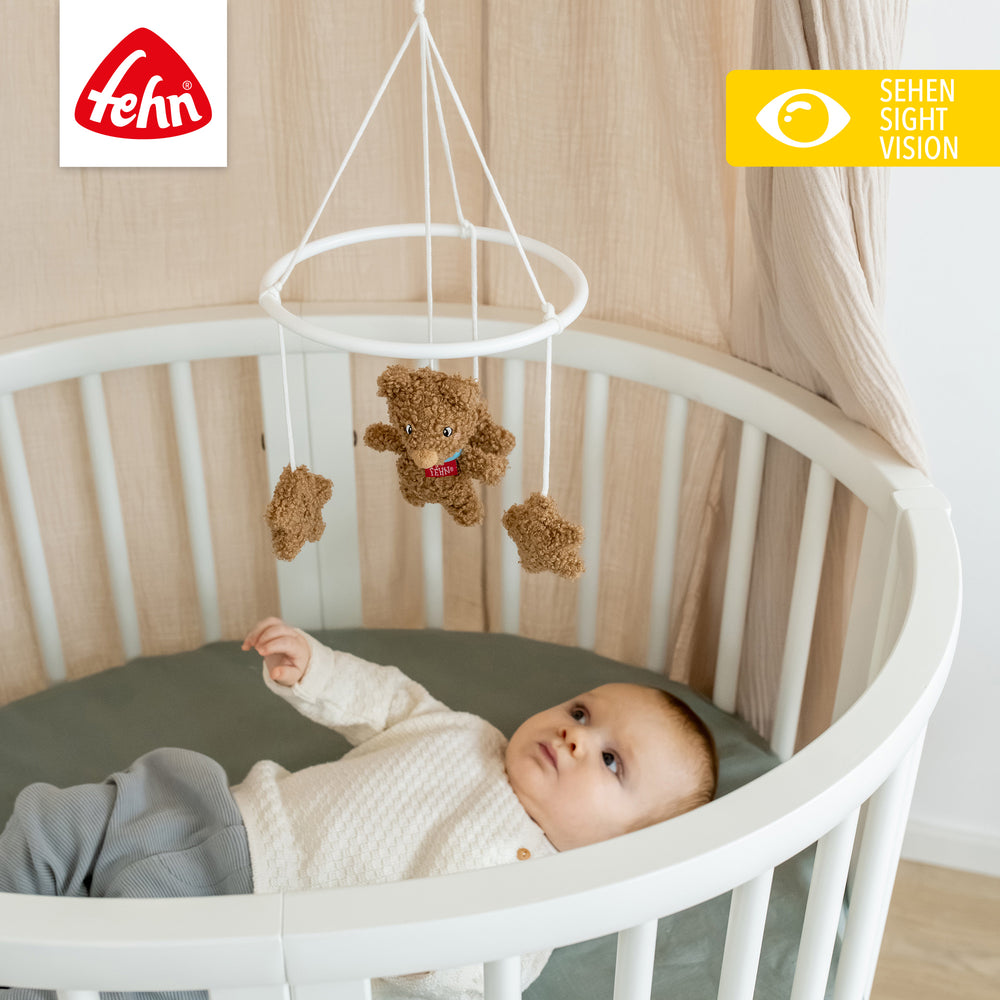 Baby liegt unter Baby Deko-Mobile Bär