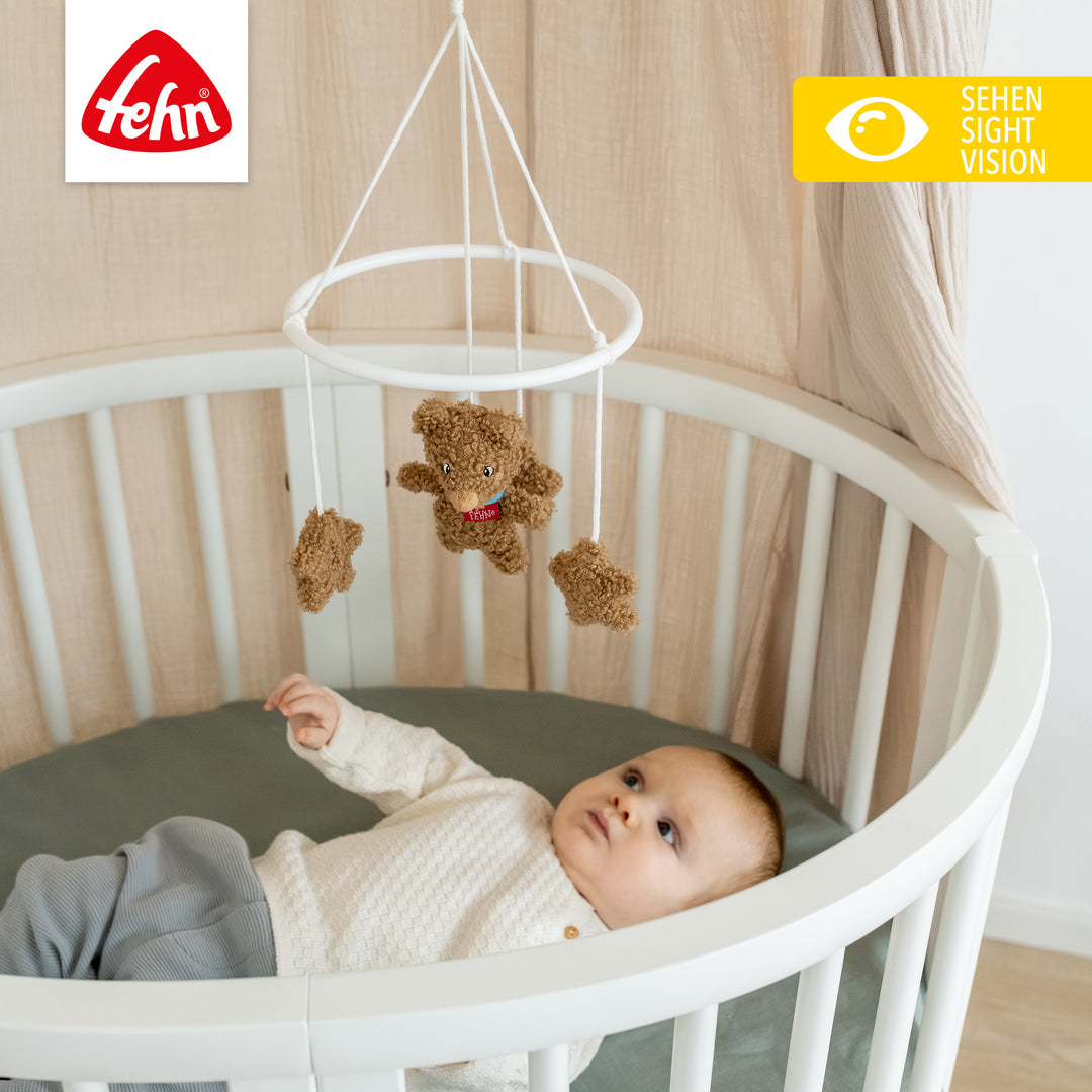 Baby liegt unter Baby Deko-Mobile Bär