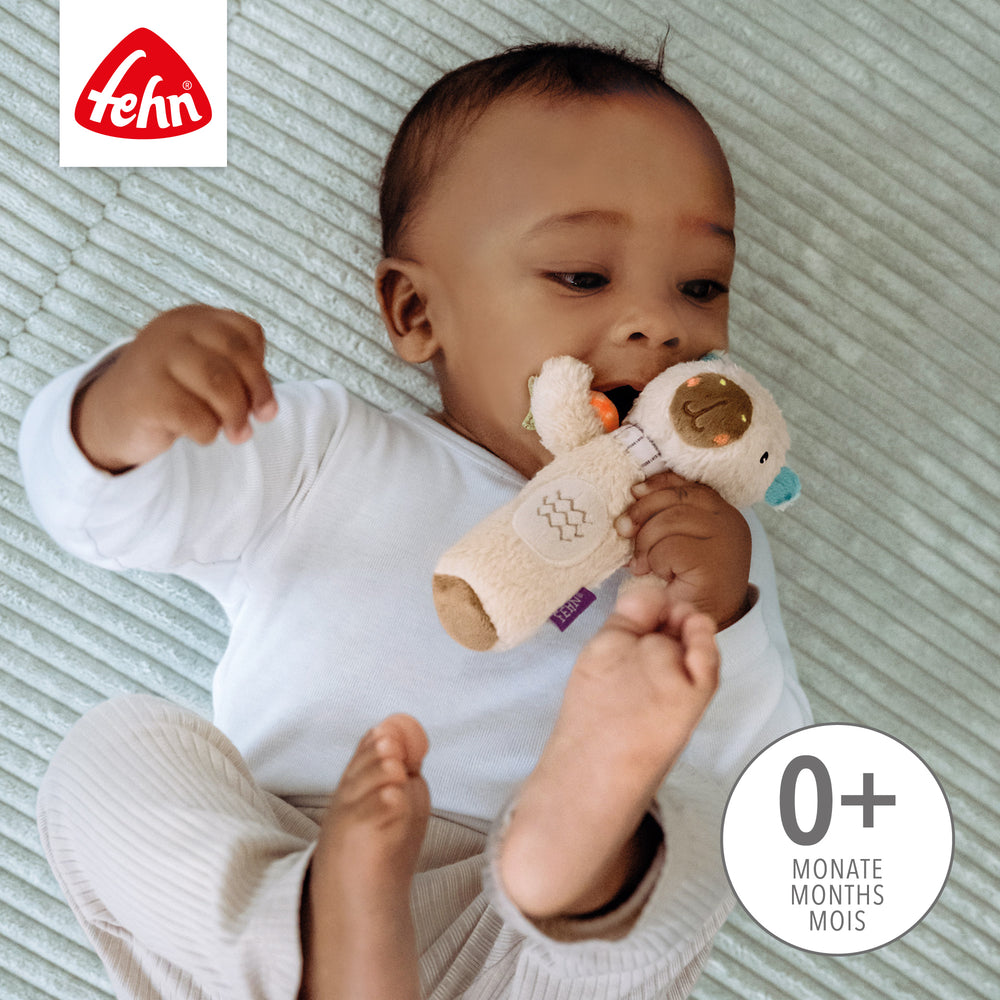 Baby spielt liegend mit Baby Stabgreifling Capybara
