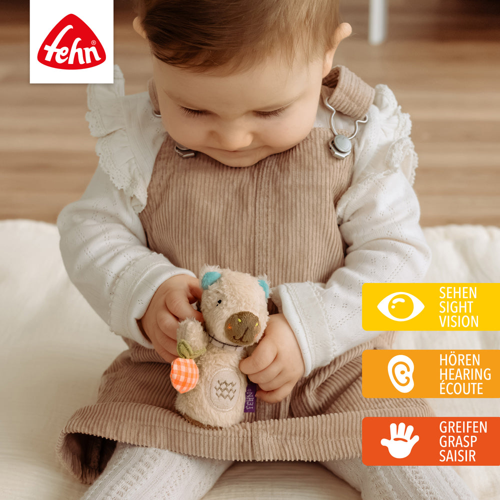 Baby spielt mit Plüsch-Mini-Rassel Capybara