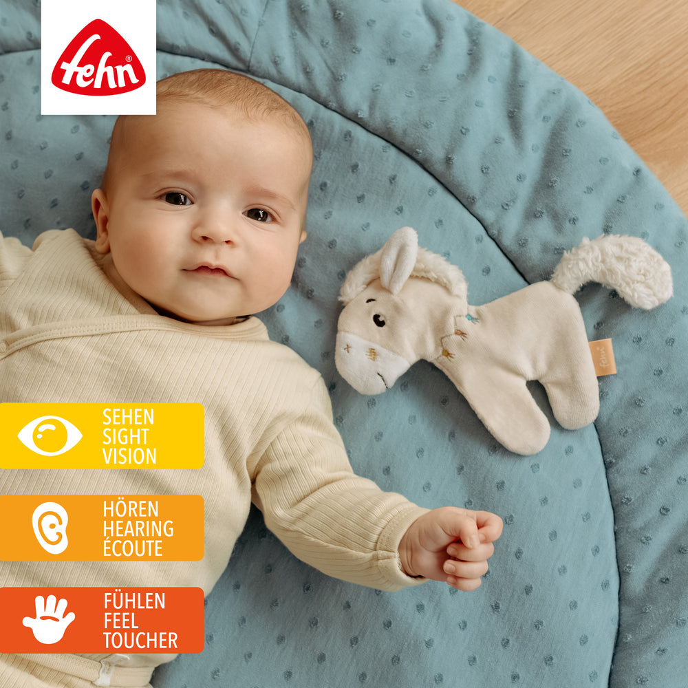 Baby liegt neben Baby Knister-Pferd
