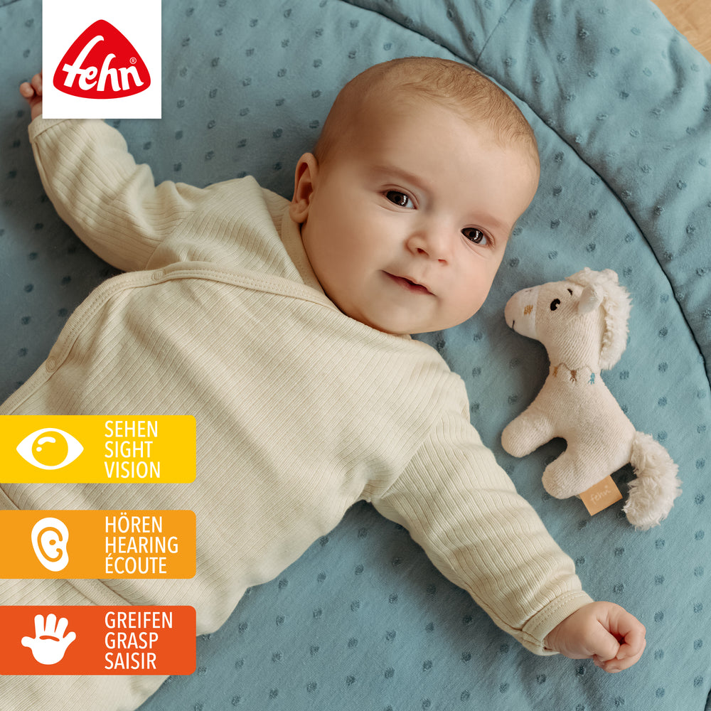Baby liegt neben Baby Mini-Rassel Pferd
