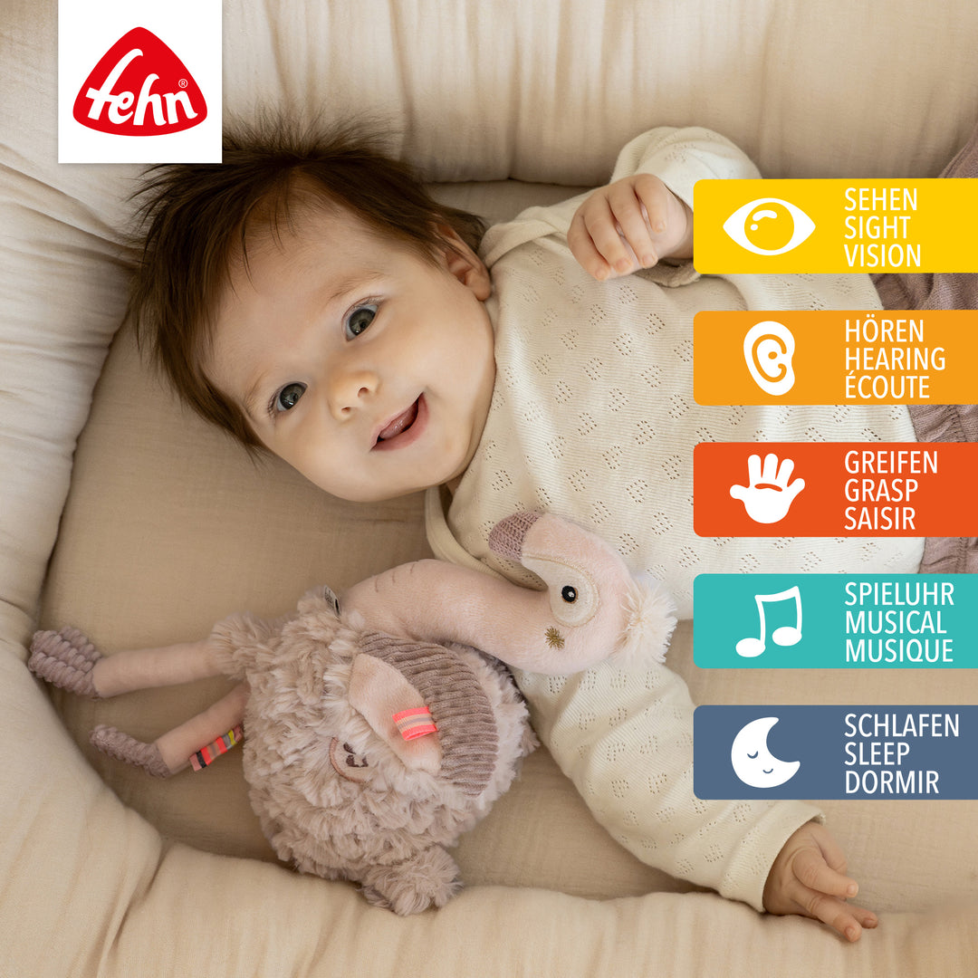 Baby liegt mit Baby Einschlafhilfe Flamingo im Babybett
