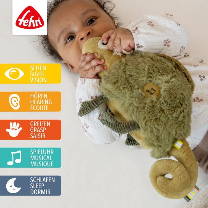 Baby liegt mit Baby Einschlafhilfe Chamäleon im Babybett