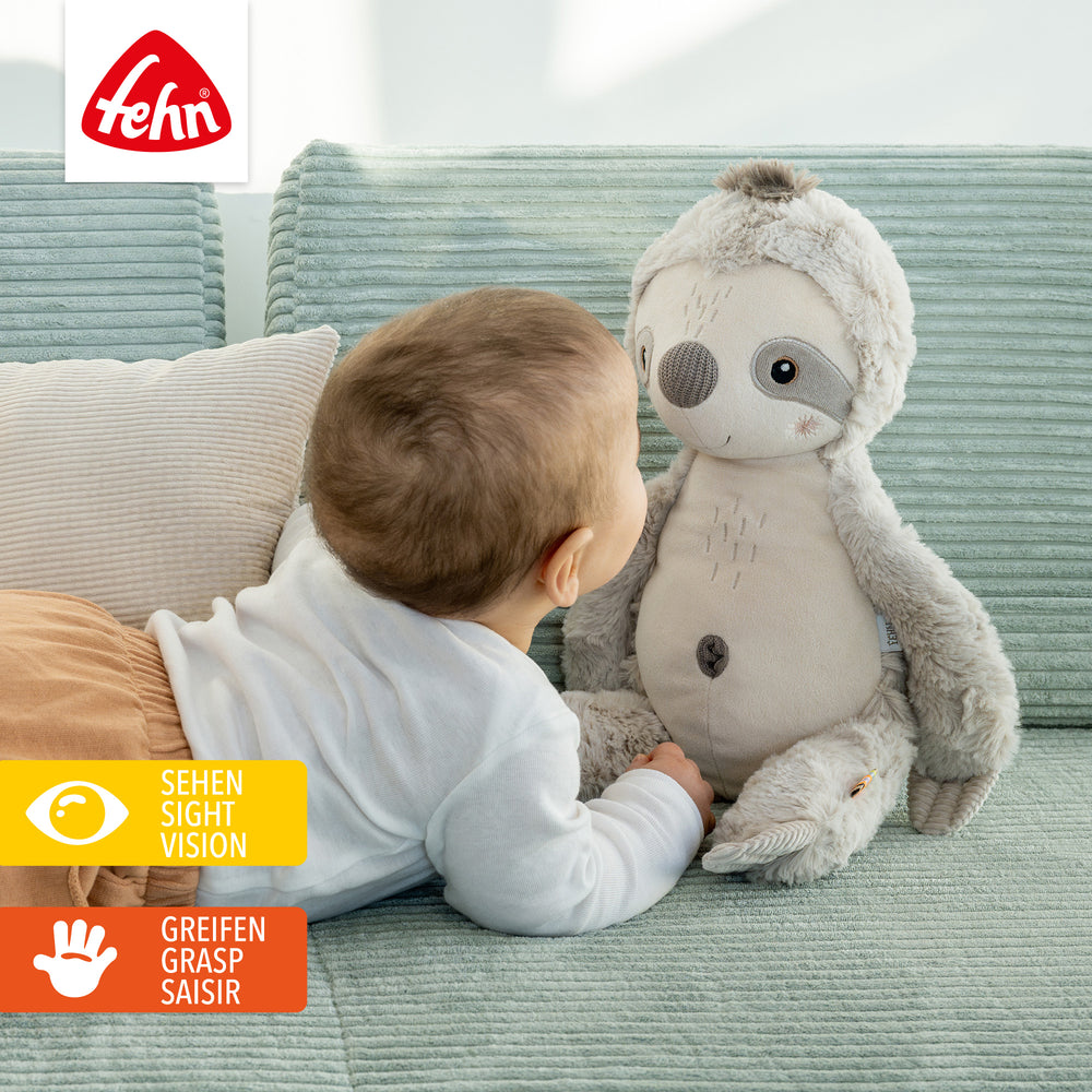Baby spielt mit Baby Kuscheltier Faultier XL