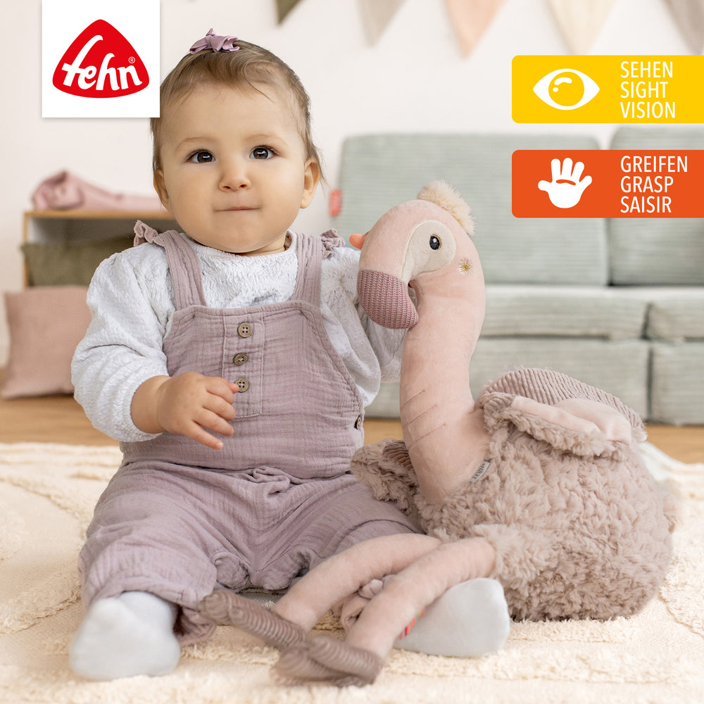 Baby spielt mit Baby Kuscheltier Flamingo XL