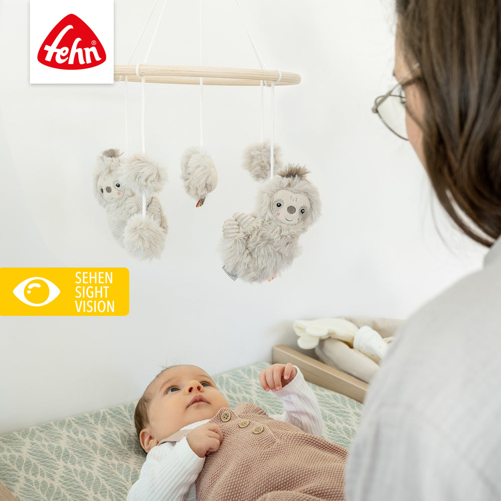 Baby liegt unter Baby Holz-Mobile Faultier