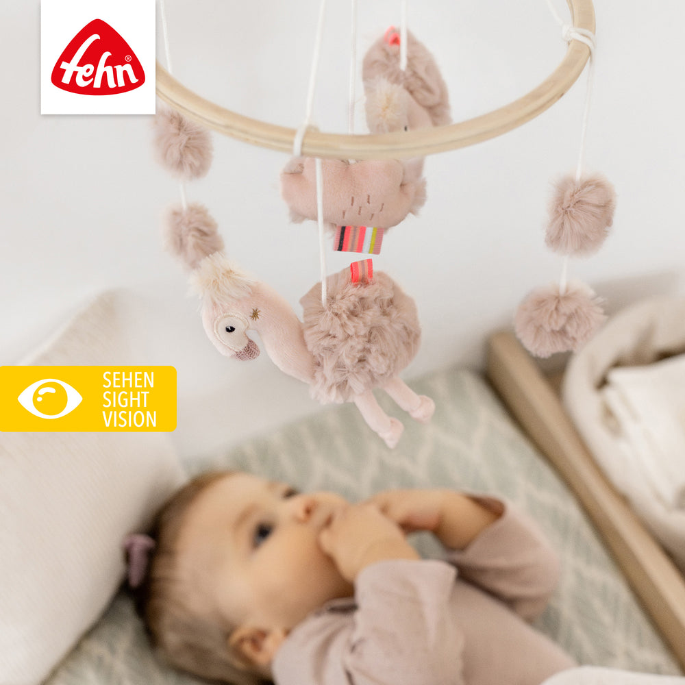 Baby liegt unter Baby Holz-Mobile Flamingo