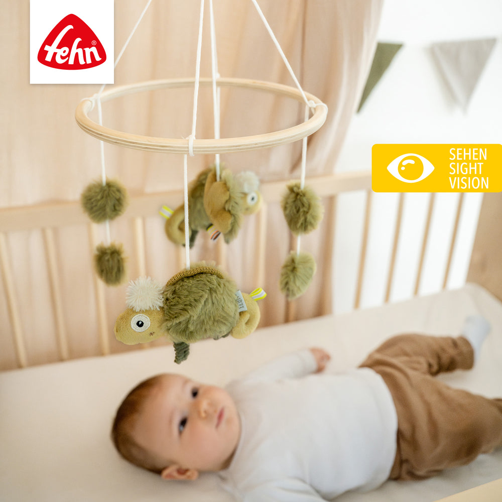 Baby liegt unter Baby Holz-Mobile Chamäleon