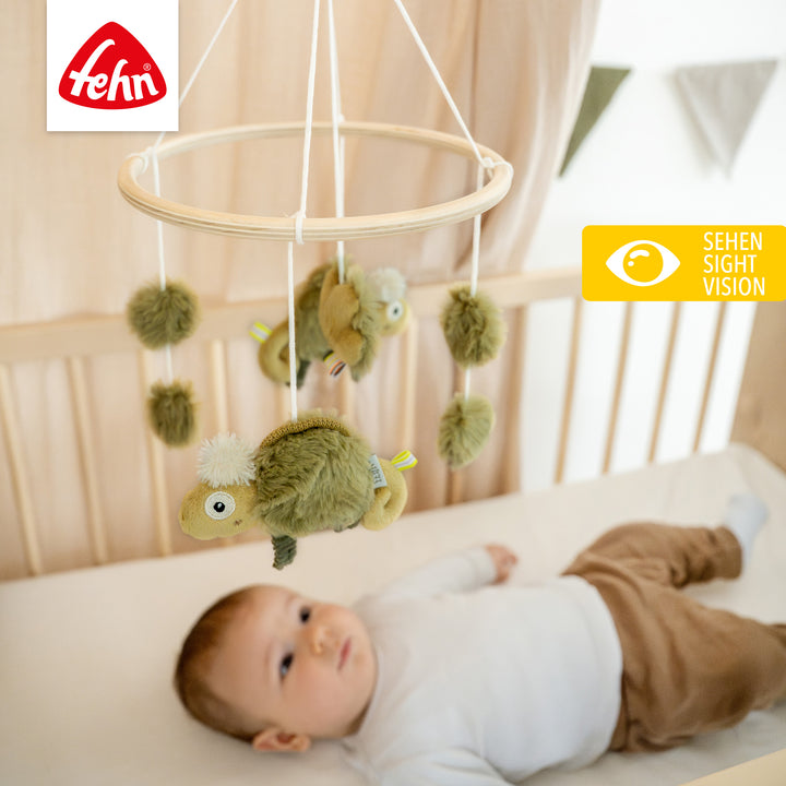 Baby liegt unter Baby Holz-Mobile Chamäleon
