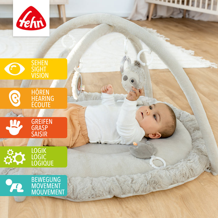 Baby liegt in Baby 3-D-Activity-Decke Faultier und greift nach Spielelement