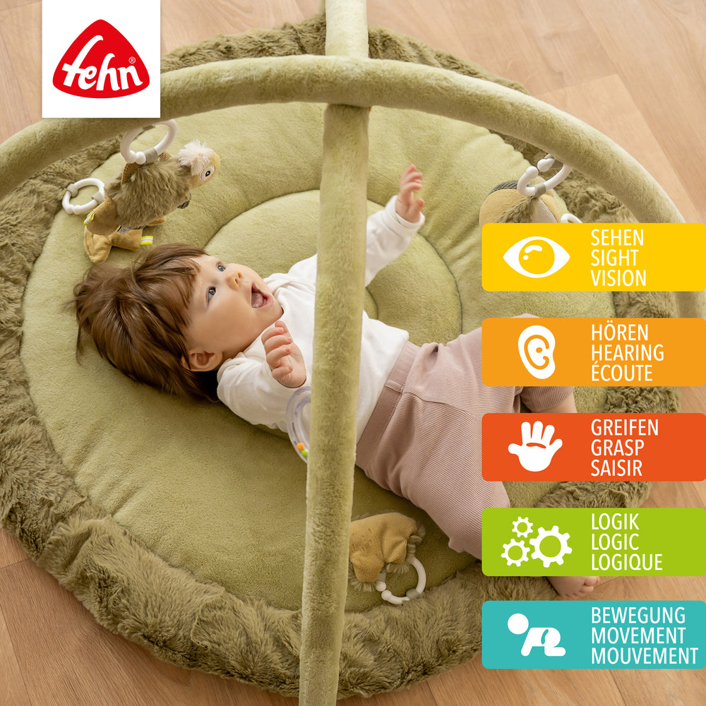 Baby liegt in Baby 3-D-Activity-Decke Chamäleon und greift nach Spielelement