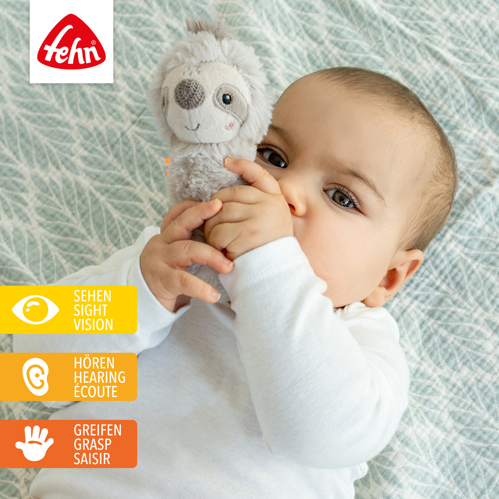 Baby hält Plüsch-Stabgreifling Faultier