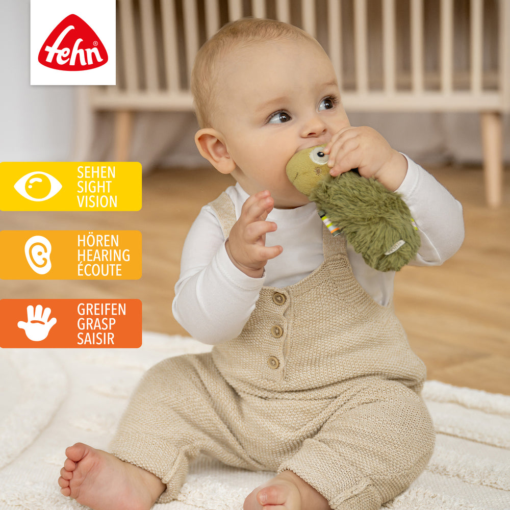Baby spielt mit Plüsch-Stabgreifling Chamäleon