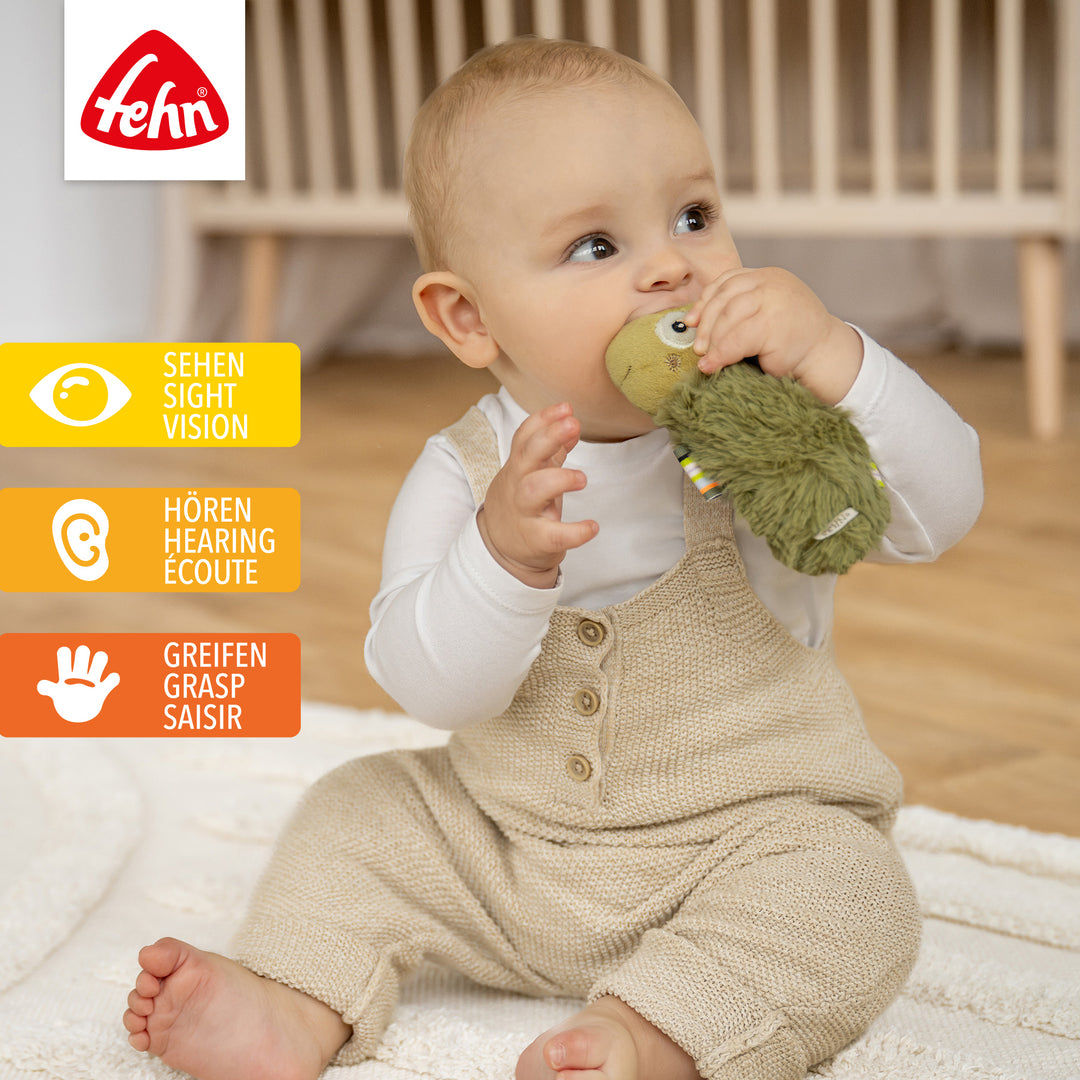 Baby spielt mit Plüsch-Stabgreifling Chamäleon
