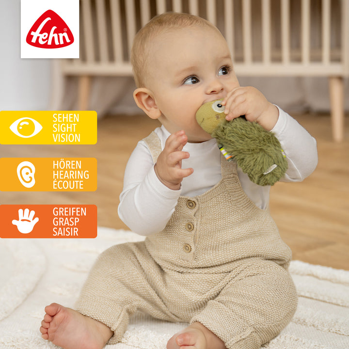 Baby spielt mit Plüsch-Stabgreifling Chamäleon