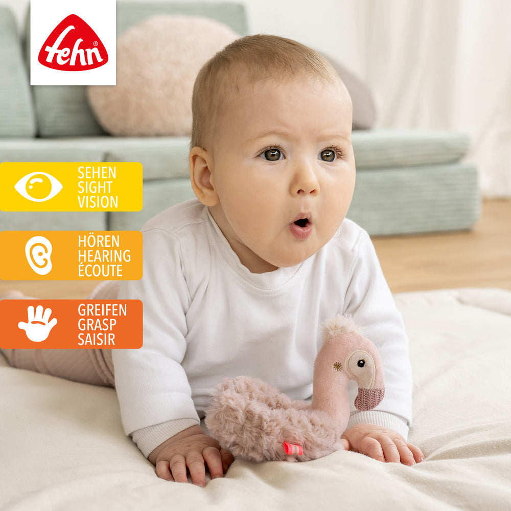 Baby spielt mit Plüsch-Ring-Greifling Flamingo