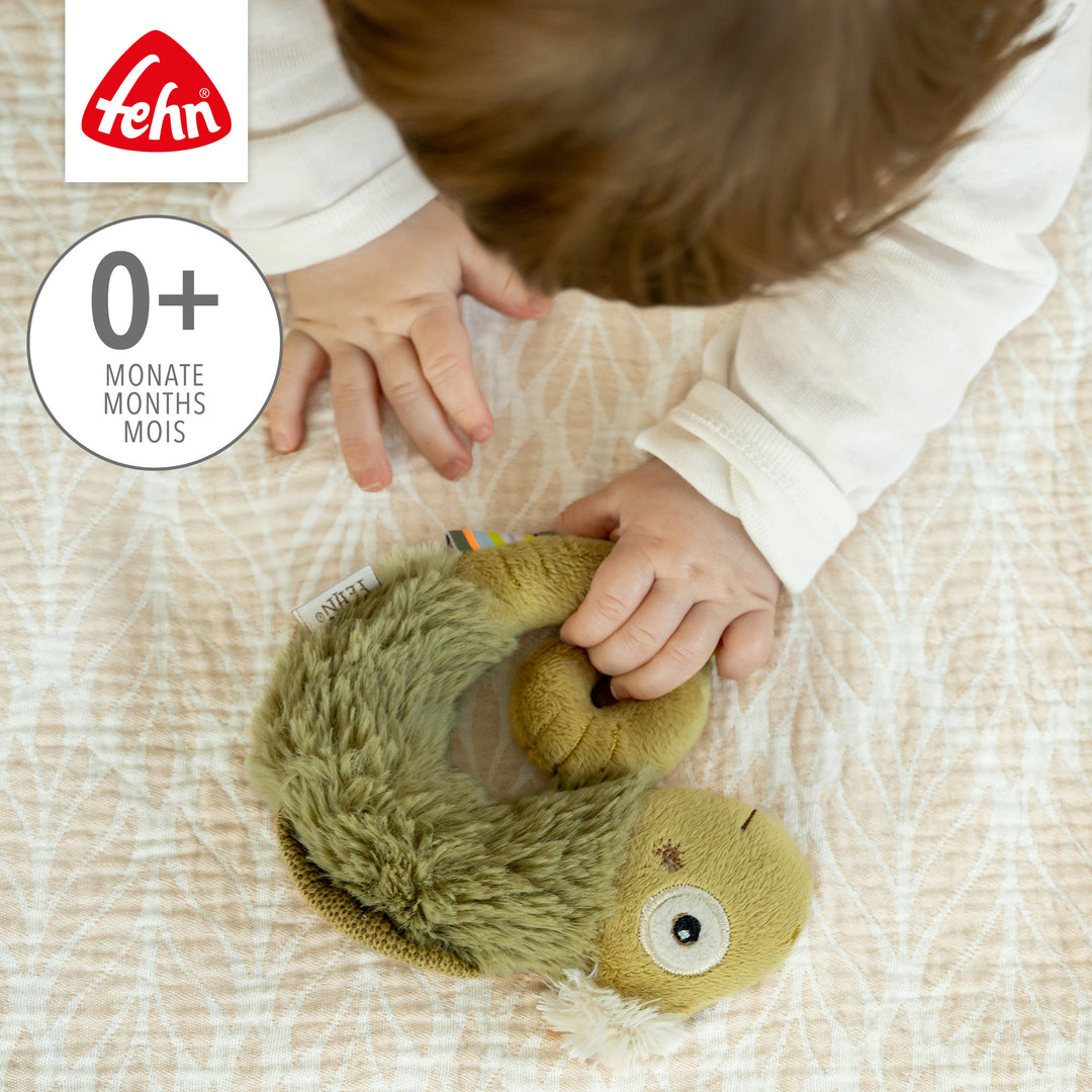 Baby greift nach Baby Ring-Greifling Chamäleon