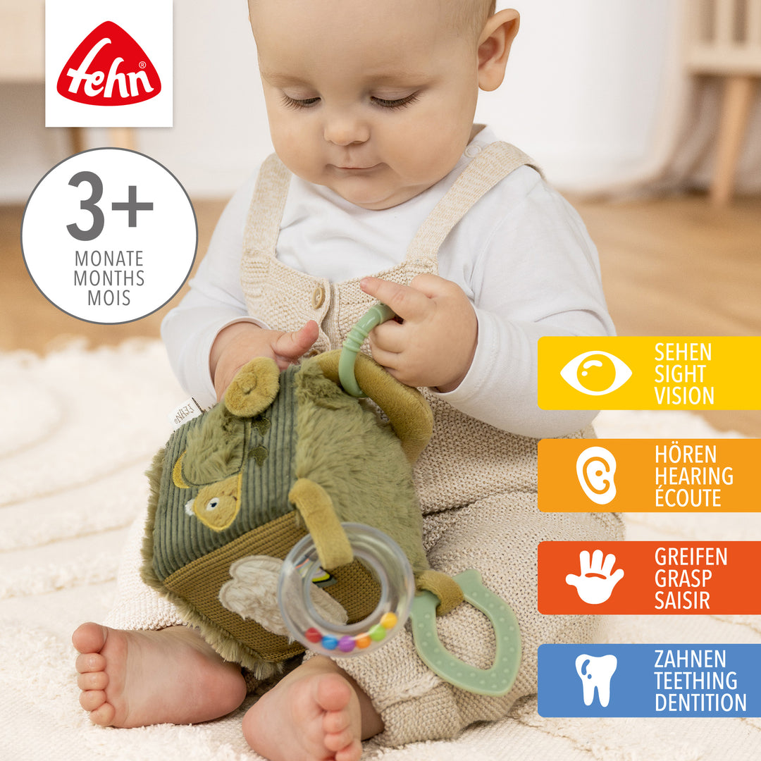 Baby spielt mit Baby Activity-Würfel Chamäleon aus weichem Plüsch