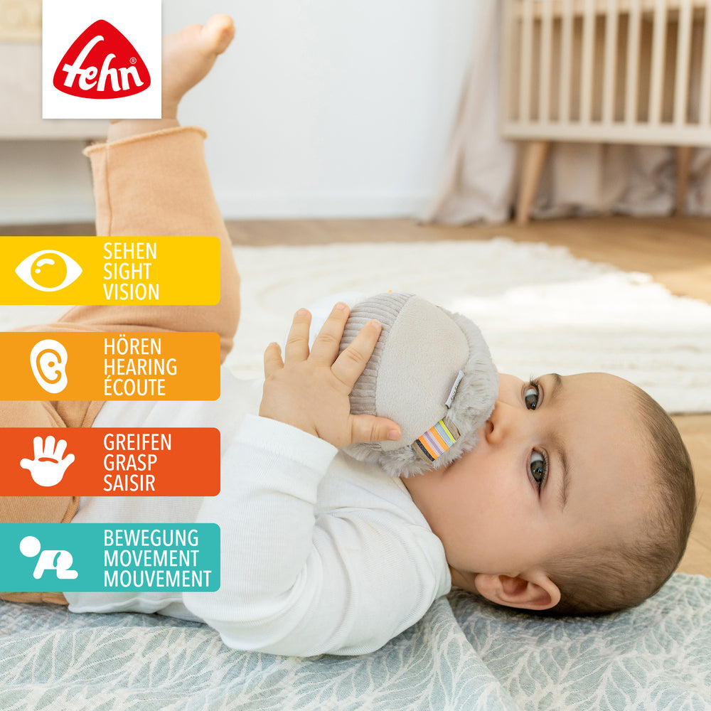 Baby hält Plüsch-Stoffball Faultier