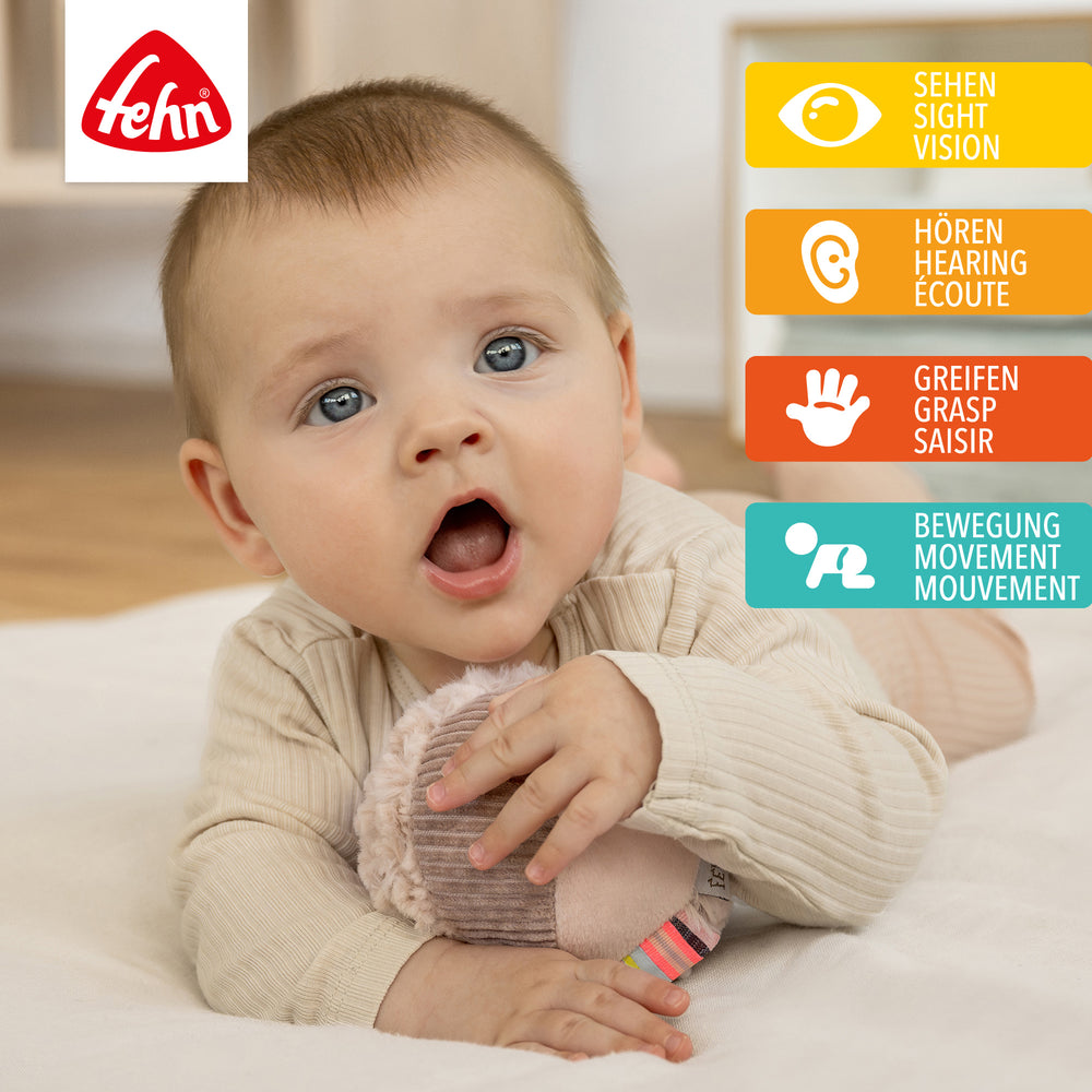 Baby spielt mit Plüsch-Stoffball Flamingo