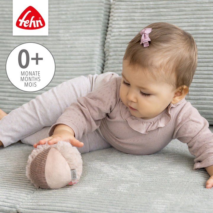Baby greift nach Baby Stoffball Flamingo