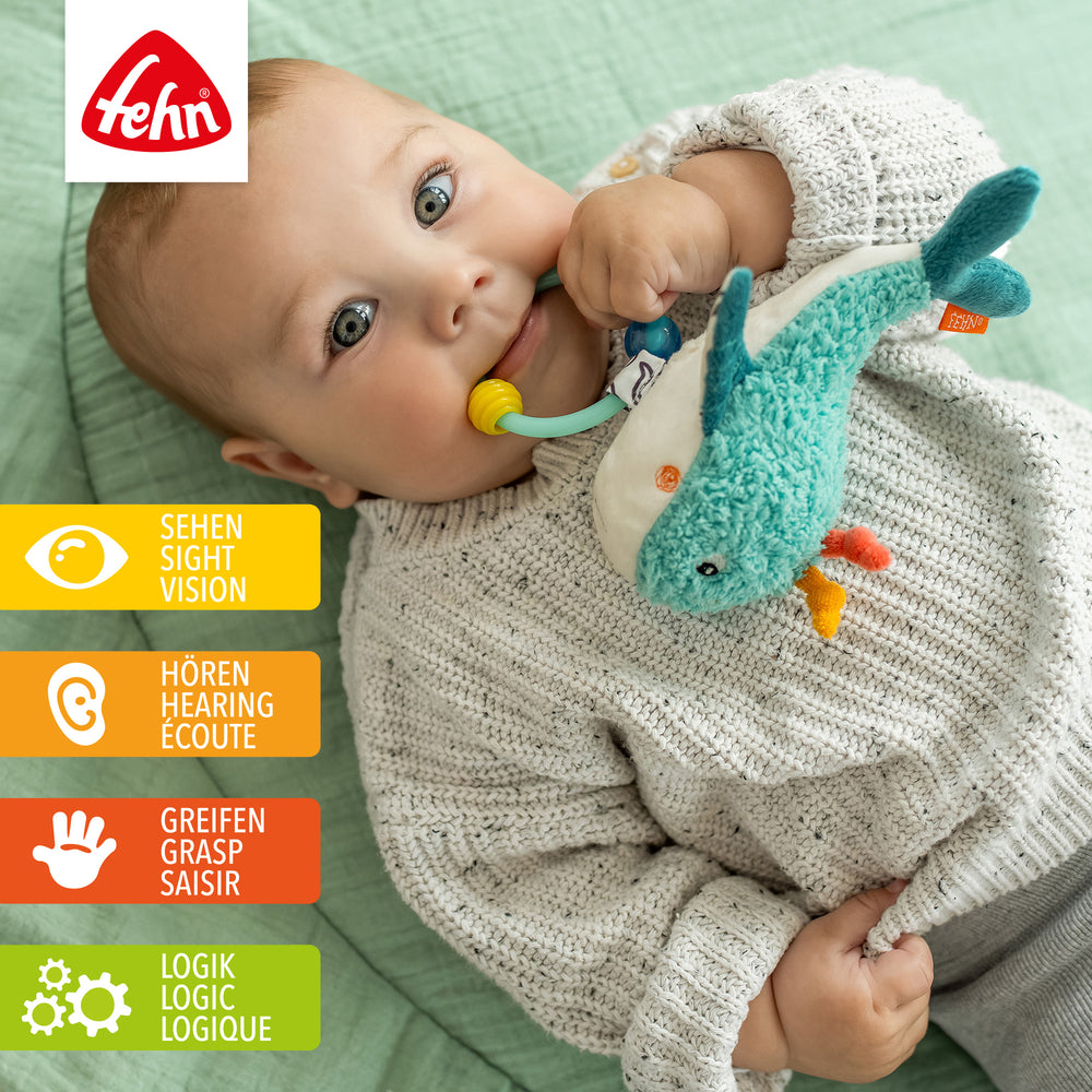 Baby spielt mit Plüsch-Perlenring Wal
