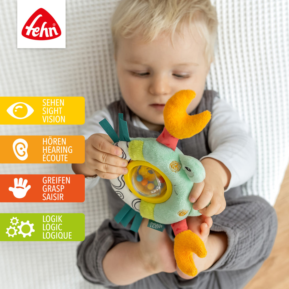 Baby spielt mit Plüsch-Drehballrassel Krabbe
