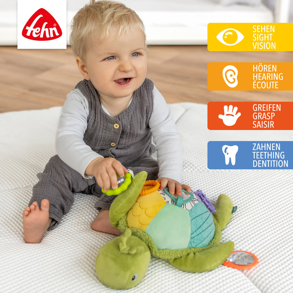 Baby spielt mit Baby Activity-Meeresschildkröte XL aus weichem Plüsch