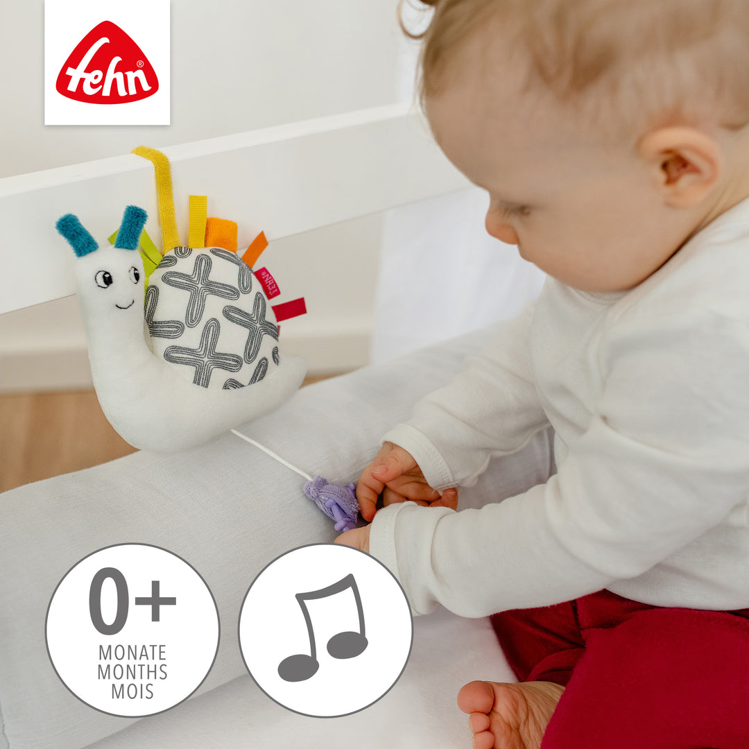 Baby spielt sitzend mit Baby Spieluhr Schnecke