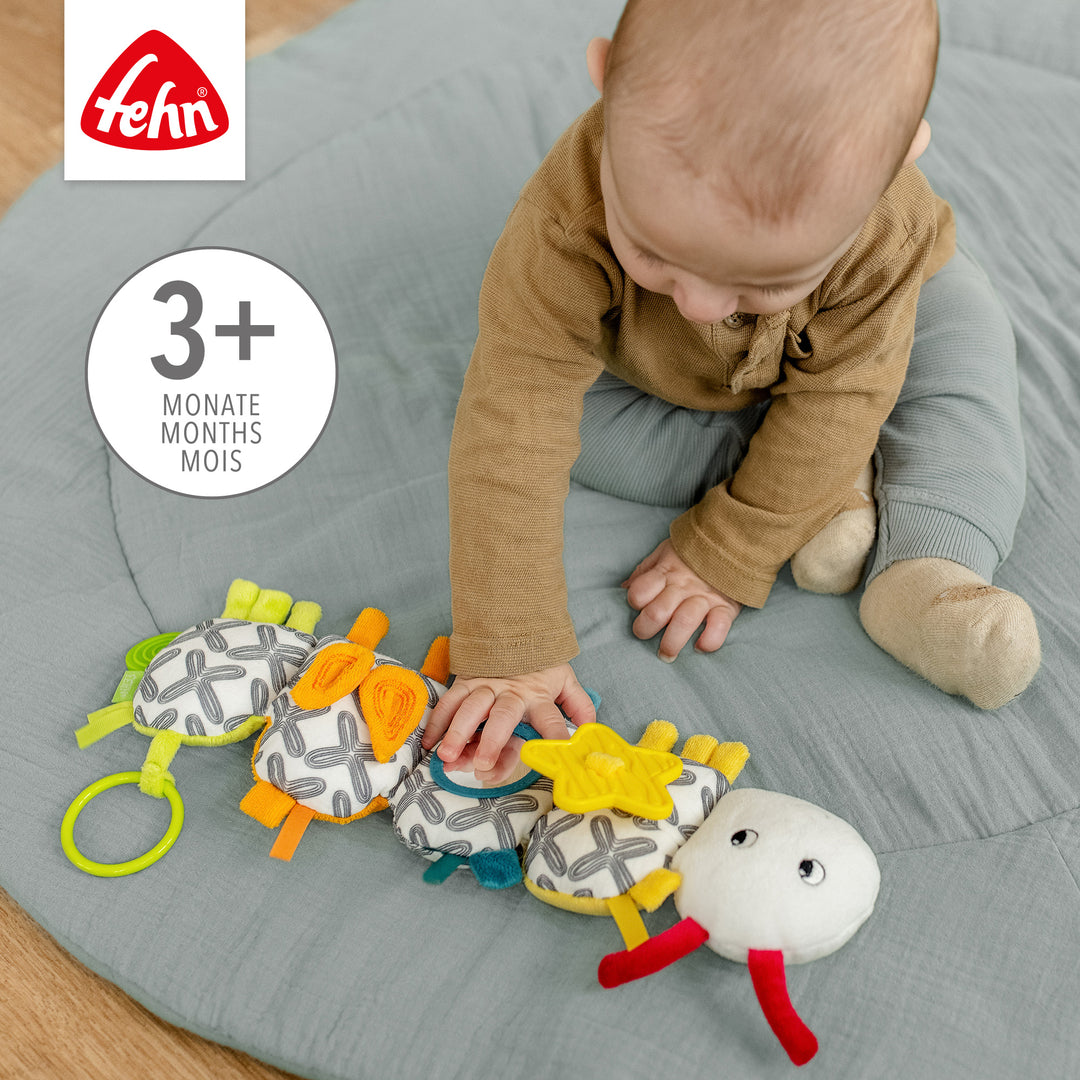 Baby greift nach Baby Activity-Raupe