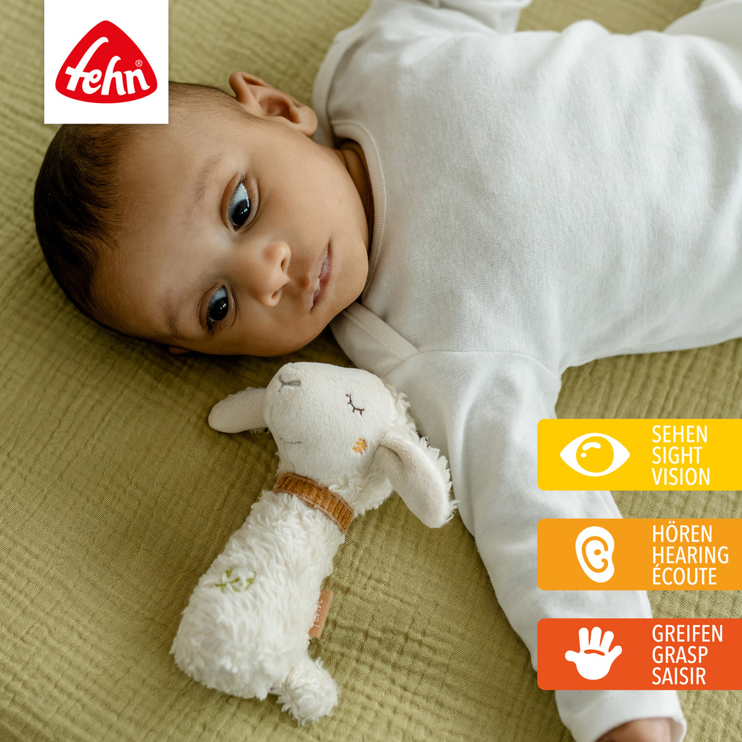 Baby spielt mit Baumwoll-Stabrassel Schaf