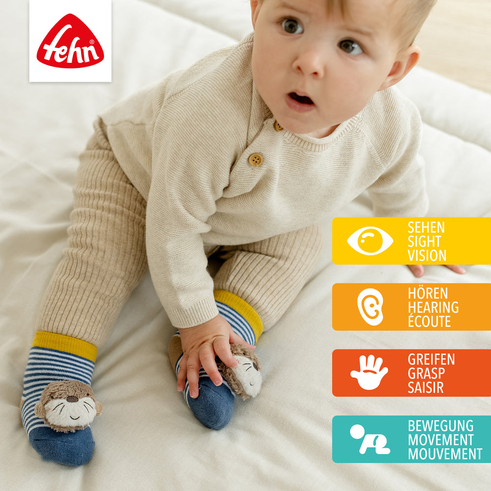 Baby trägt Baby Rasselsocken Otter an den Füßen