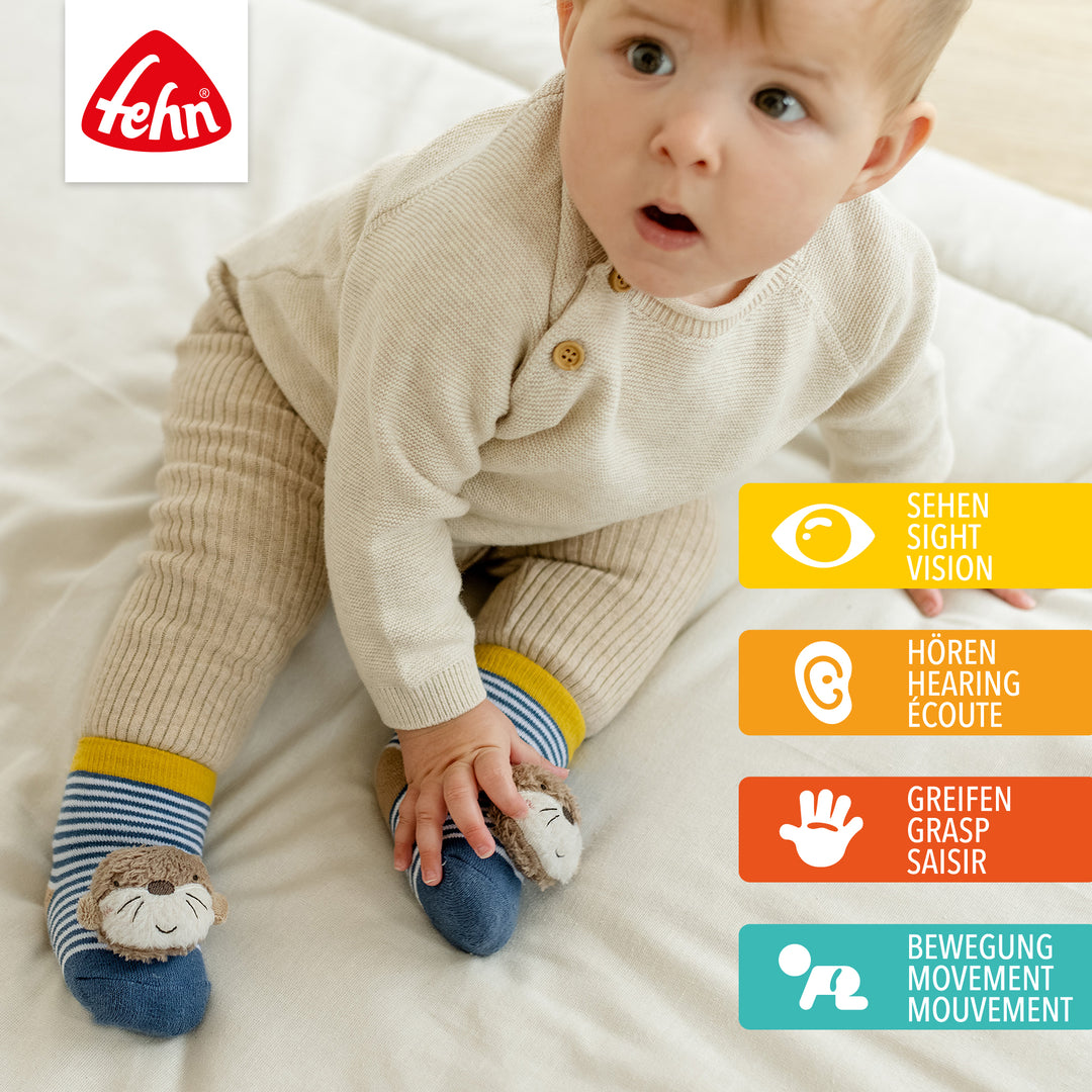 Baby trägt Baby Rasselsocken Otter an den Füßen
