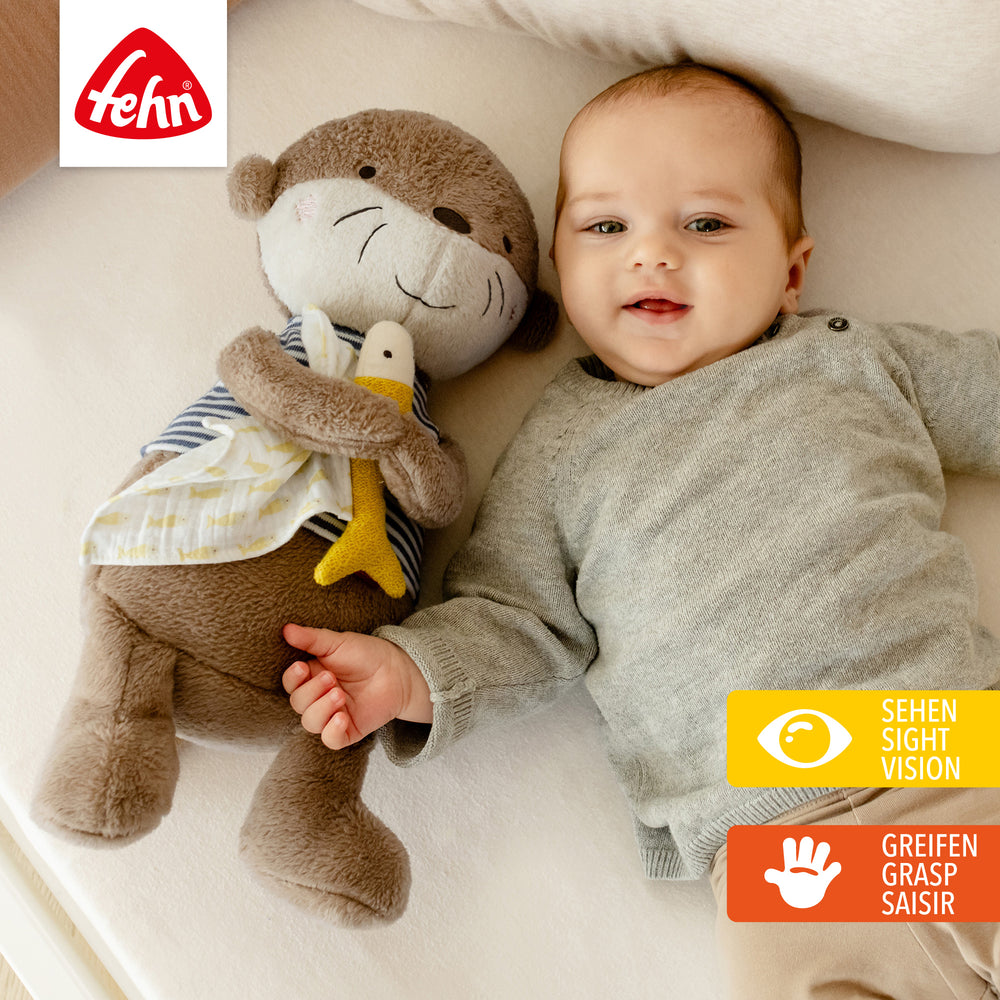 Baby liegt neben Baby Kuscheltier Otter XL
