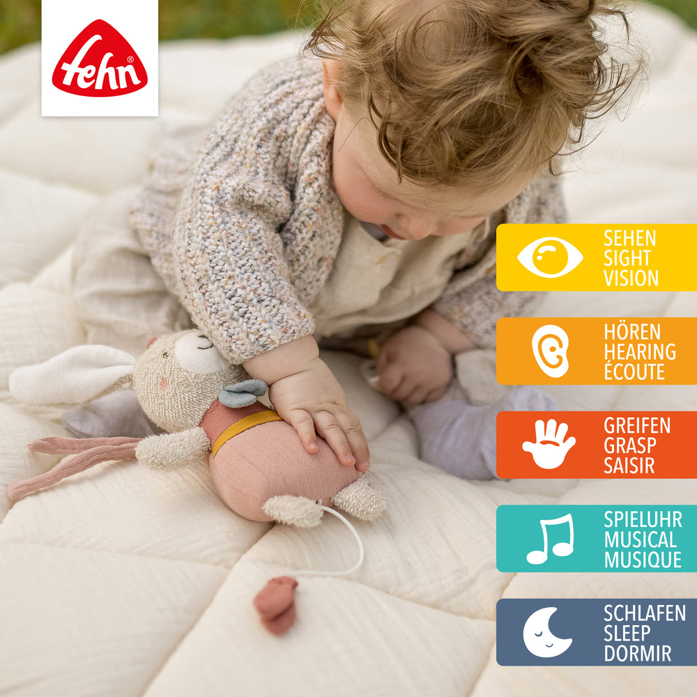 Baby spielt sitzend mit Baby Spieluhr Hase