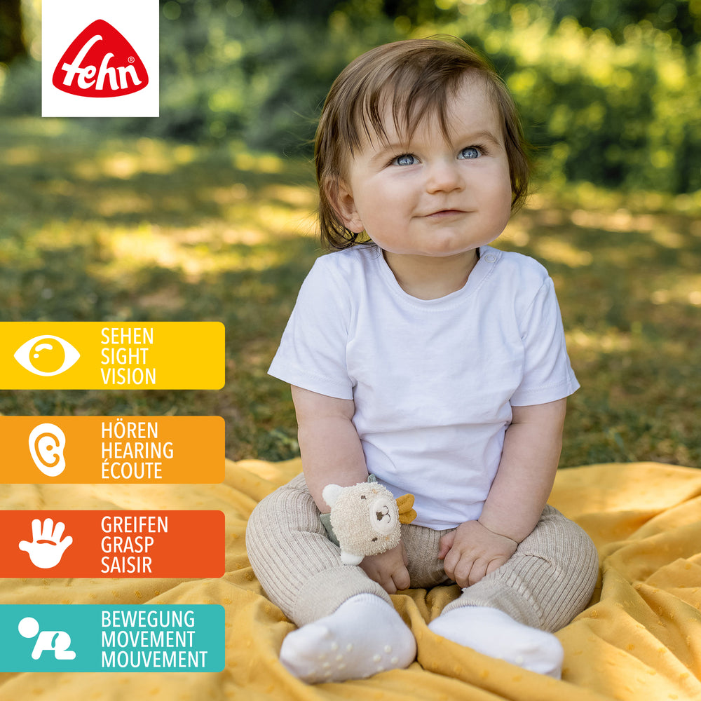 Baby spielt mit Baumwoll-Rasselarmband Bär