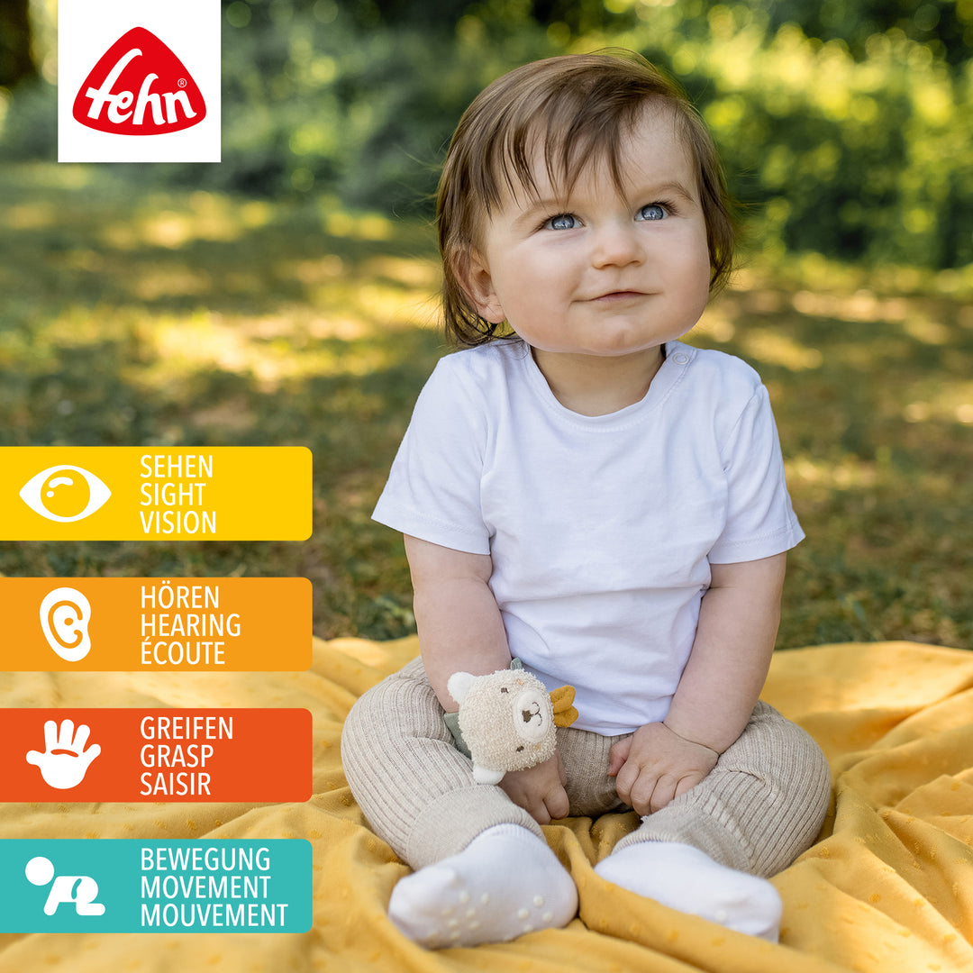 Baby spielt mit Baumwoll-Rasselarmband Bär