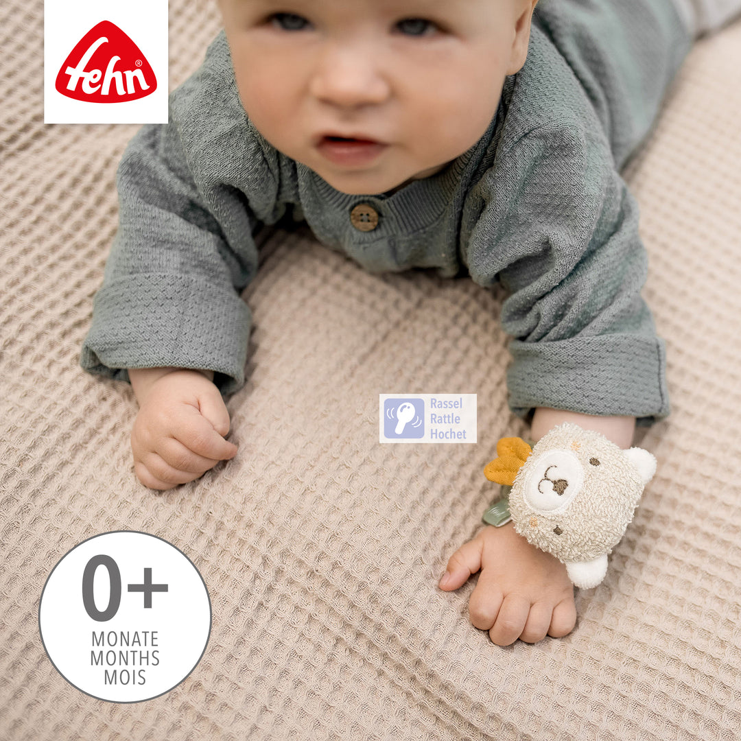 Baby krabbelt mit Baby Rasselarmband Bär am Handgelenk