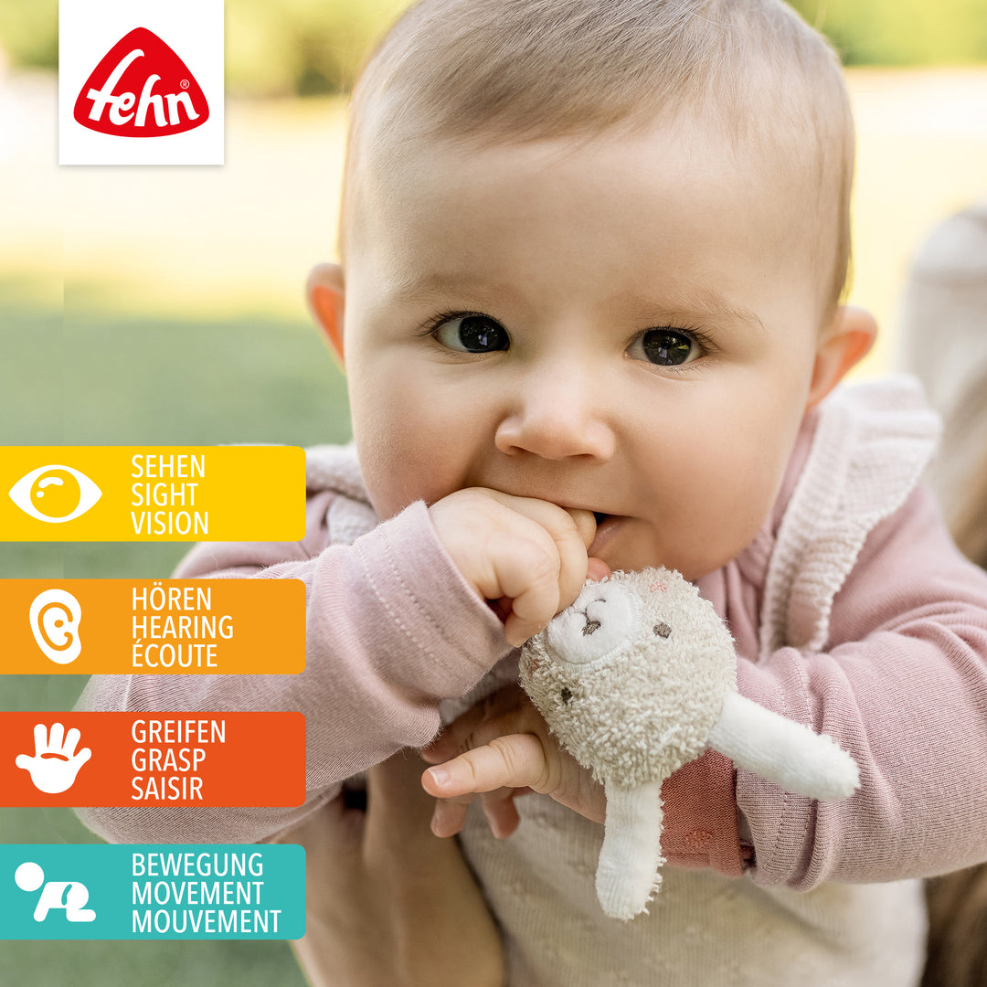 Baby spielt mit Baumwoll-Rasselarmband Hase