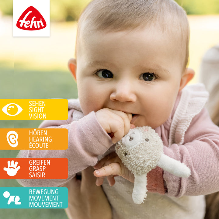 Baby spielt mit Baumwoll-Rasselarmband Hase