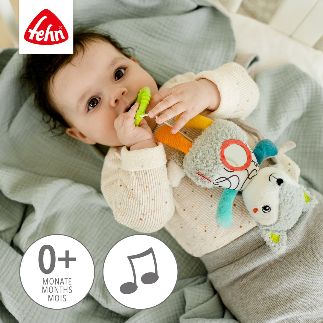 Baby spielt liegend mit Baby Spieluhr Fuchs