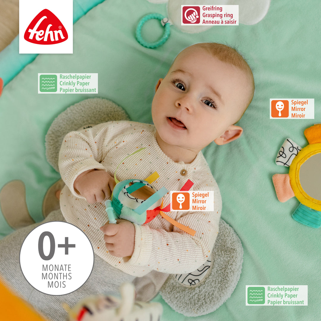 Baby liegt in Baby 3-D-Activity-Decke Koala und spielt mit Spielelement