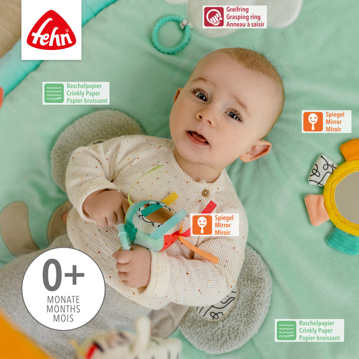 Baby liegt in Baby 3-D-Activity-Decke Koala und spielt mit Spielelement