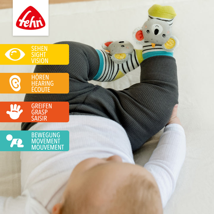 Baby trägt Baby Rasselsocken Koala an den Füßen