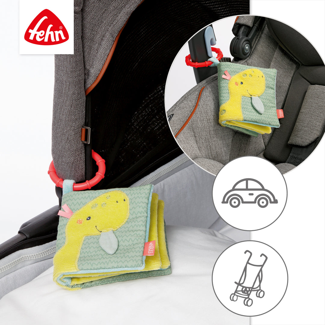 Baby Stoffbuch Happy Dino an Kinderwagen und Babyschale befestigt
