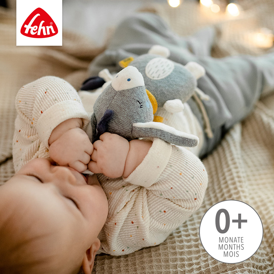 Baby spielt liegend mit Baby Spieluhr Esel