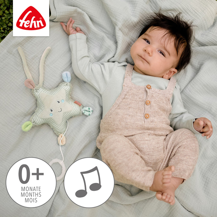 Baby spielt liegend mit Baby Spieluhr Seestern