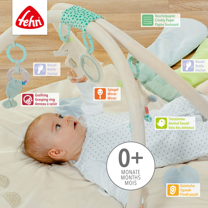 Baby liegt in Baby 3-D-Activity-Decke Oktopus und greift nach Spielelement