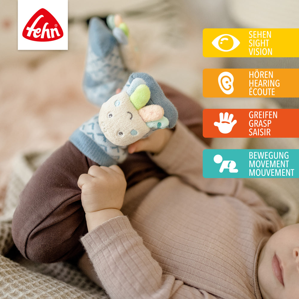 Baby trägt Baby Rasselsocken Oktopus an den Füßen